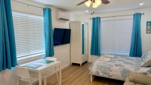 a bedroom with blue curtains and a table and a bed at Seashell 8 - Seasonal Rental in Boynton Beach +2 photos