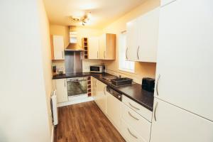 a kitchen with white appliances and wooden floors at Dalby House in Derby