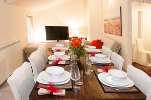 tavolo da pranzo con piatti bianchi e fiocchi rossi di La Casa Di Luigi a Gratacasolo