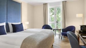 a hotel room with a bed and a table and chairs at Dorint Parkhotel Meißen in Meißen