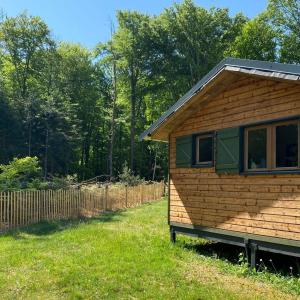 a wooden cabin in a yard with a fence at Camping Le Vert-Bois - Corrèze in Saint-Martin-la-Méanne