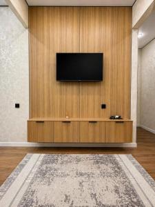 a living room with a television on a wooden wall at Olympic Park Apartments near Almaty Arena in Almaty