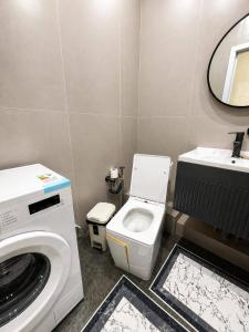 a bathroom with a washing machine and a toilet at Olympic Park Apartments near Almaty Arena in Almaty