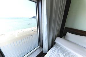 a bedroom with a window with a view of the ocean at Hamduk Pungkyungchae Pension in Jeju