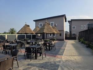 an outdoor patio with tables and chairs and umbrellas at KayQuin Garden in Warri