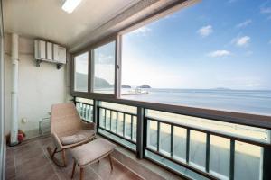 a balcony with two chairs and a view of the ocean at Wando Love You Pension in Wando