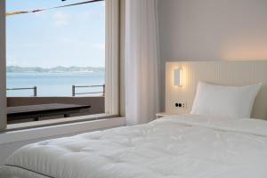 a bedroom with a large white bed and a large window at Wando Love You Pension in Wando