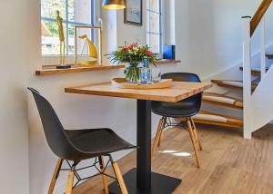 a dining room table with two chairs and a vase of flowers at Reethaus M - Sommerhaus 54 in Grödersby