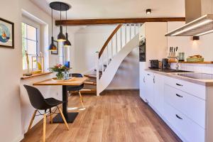a kitchen and dining room with a table and a staircase at Reethaus M - Sommerhaus 54 in Grödersby