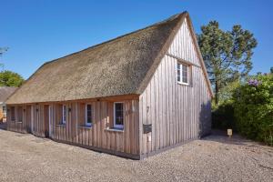 a large wooden building with a thatched roof at Reethaus L - Sommerhaus 54 in Grödersby