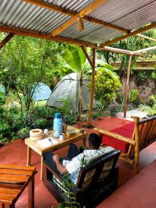 a man sitting at a table under a pergola at Kilimanjarosons homestay in Moshi