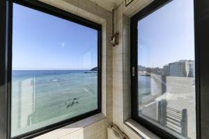 a room with a window with a view of the ocean at Hamduk Pungkyungchae Pension in Jeju +14 photos