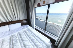 a bedroom with a bed and a view of the ocean at Hamduk Pungkyungchae Pension in Jeju
