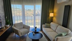 a living room with a couch and chairs and a large window at Jeziorna Premium Apartment in Siewierz