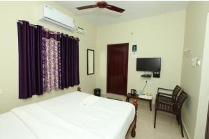 a bedroom with a white bed and a tv at Ecovilla luxury in Pondicherry