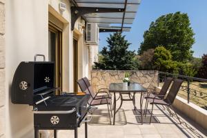 a grill and a table and chairs on a balcony at Villa Granero by Booking Kottas in Kassandra