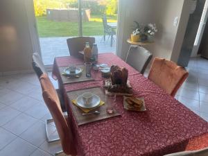 a dining room table with a red table cloth and chairs at Brigitte Olivier in Teloché