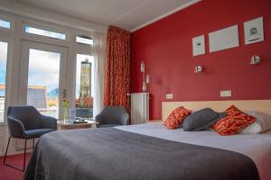 a bedroom with red walls and a bed with two chairs at Hotel Oepkes in West-Terschelling +47 photos