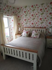 ein Schlafzimmer mit einem Bett mit Blumen an der Wand in der Unterkunft The Old Medical Hall in Castletownbere