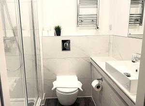 a white bathroom with a toilet and a shower at Goodmayes Grand Hotel in Goodmayes