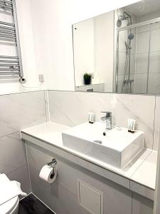 a white bathroom with a sink and a mirror at Goodmayes Grand Hotel in Goodmayes