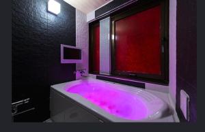 a bathroom with a pink bath tub with a window at ホテルヴェローナ in Yokohama