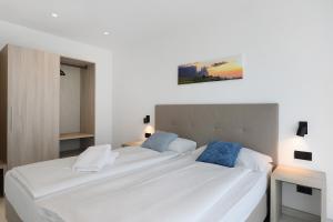 a bedroom with two beds with white sheets and blue pillows at Bike Apartments Curti - Himmelblau in Laives