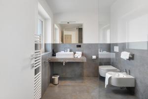 a bathroom with two sinks and a toilet and a mirror at Bike Apartments Curti - Himmelblau in Laives +31 photos