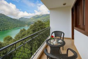 a balcony with two chairs and a table with a view of a river at Hotel Morning Lake in Nainital