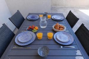 a table with plates of food and a bowl of fruit at Cozy Cottage with Spa - Welkeys in Moliets-et-Maa