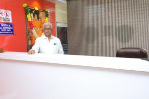 a man standing behind a desk in a room at SSR Hotel in Srikalahasti