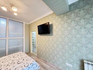 a bedroom with a bed and a tv on the wall at RentDay Botanica in Chişinău