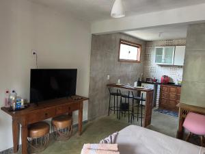a living room with a television and a table and a kitchen at Bangalo Bela Vista in Caparaó Velho +9 photos