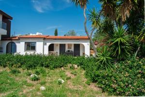 a white house with a palm tree and a yard at Villa Leda - The Guest Wing in Paphos