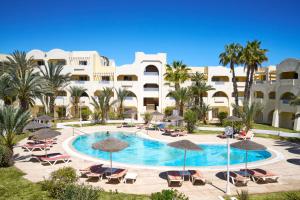 a pool with chairs and umbrellas in front of a building at Medina Les Quatre Saisons Aqua Park Resort and Thalasso Djerba in Djerba