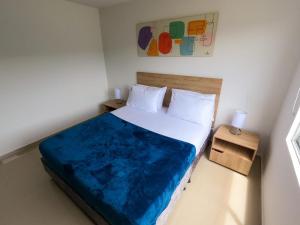a bedroom with a large bed with a blue blanket at Apartamentos Quedate en Anavi San Gil Plaza in San Gil +14 photos