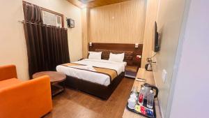 a hotel room with a bed and a chair at Hotel Red Sapphire Kushinagar in Kushinagar