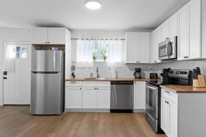 a kitchen with white cabinets and a stainless steel refrigerator at Mins to Downtown Chic & Modern - Elegant in Noir in Chattanooga