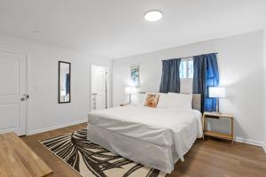 a white bedroom with a white bed and blue curtains at Mins to Downtown Chic & Modern - Elegant in Noir in Chattanooga
