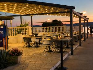 a patio with tables and chairs under a pergola with lights at Hotel Millenium deluxe in Selce