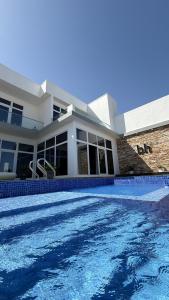 a house with a swimming pool in front of a house at bh villa in Al Sharqiyah