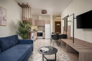 a living room with a blue couch and a kitchen at KLG Studios and Apartment in Nikiti