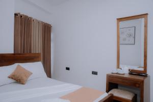 a bedroom with a bed and a desk and a mirror at Blue9 Hotel in Jaffna