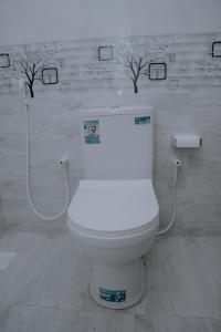 a white toilet in a bathroom with trees on the wall at Blue9 Hotel in Jaffna