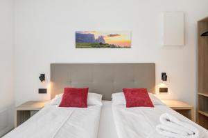 a bedroom with two beds with red pillows at Bike Apartments Curti - Abendrot in Laives