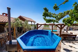 a blue tub in a yard with a table and a tree at My Dalmatia - Hilltop Paradise with private pool, sauna and Jacuzzi in Kula Atlagić