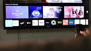 a person holding a cell phone in front of a television at bh villa in Al Sharqiyah