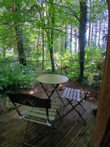 a table and two chairs on a wooden deck at Le Temple Ysambre in Malansac