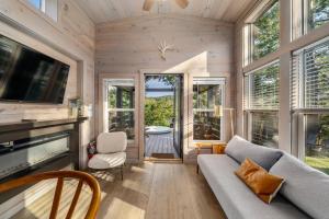 a living room with a couch and a tv and windows at Asheville River Cabins, WorldHotels Backdrop in Arden