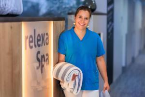 a woman in a blue shirt holding a stack of towels at relexa hotel Bad Steben in Bad Steben +66 photos